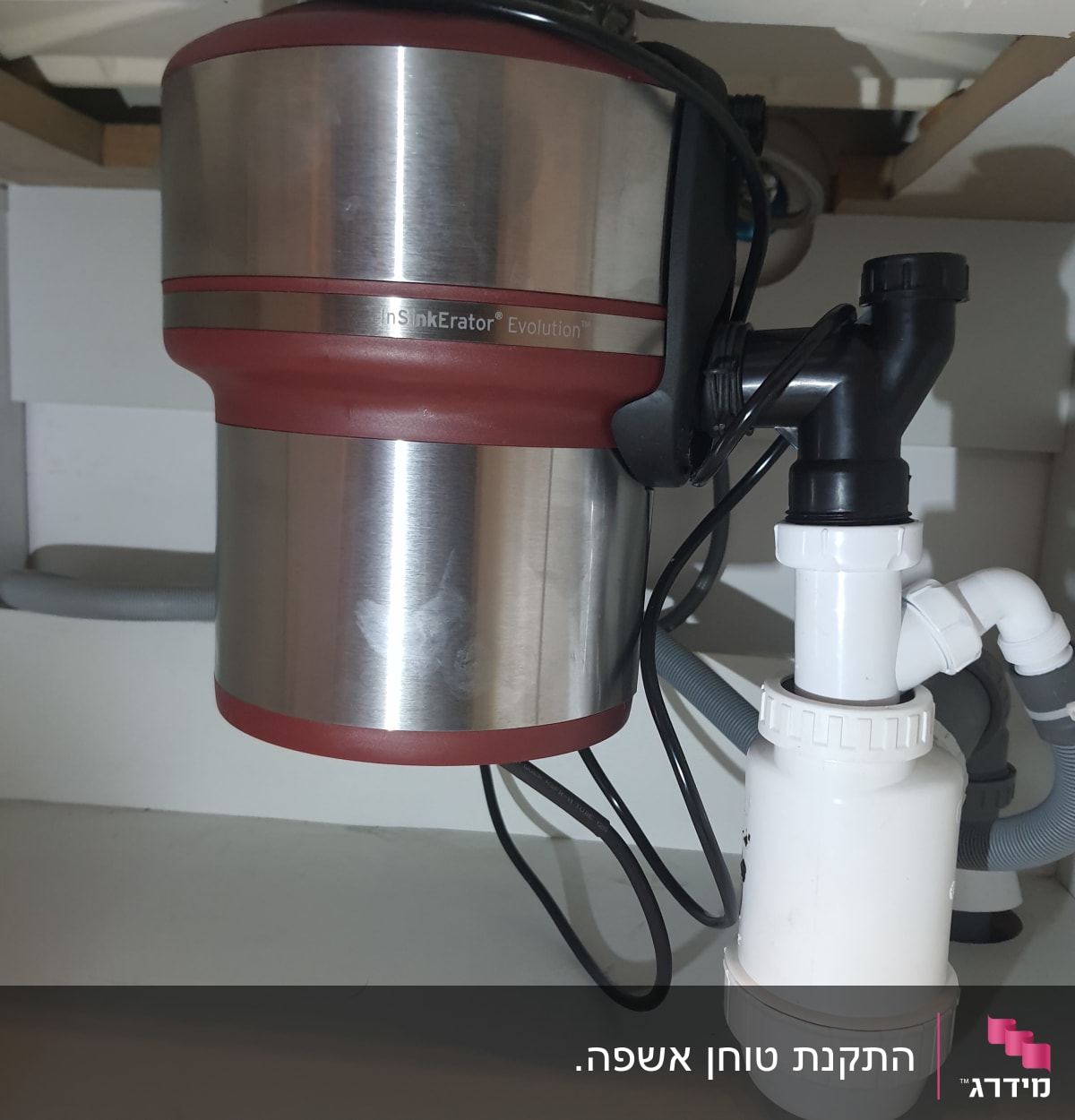 מכשיר טוחן אשפה מתחת לכיור עם צינורות חיבור